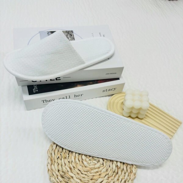 White slippers displayed on a clean surface with a textured sole